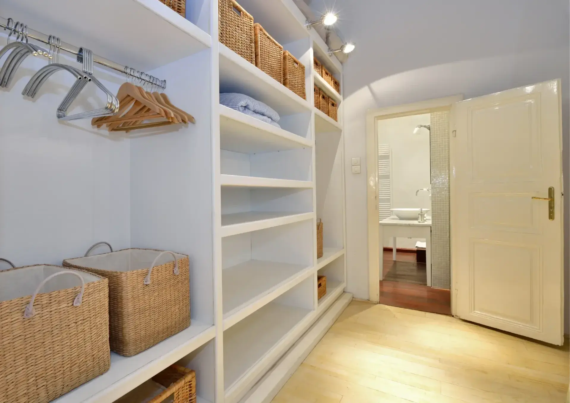 Renovatie van een klassieke woning door Walraven Bouw: stijlvolle badkamer en inloopkast met houten vloeren en witte gelakte deuren